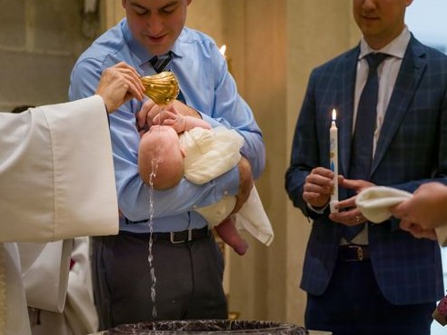 baby held by her father being baptized